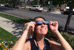 Rachel Nania, Living Editor at WTOP, takes a quick break from work to look up at the eclipse. (WTOP/Sarah Beth Hensley)