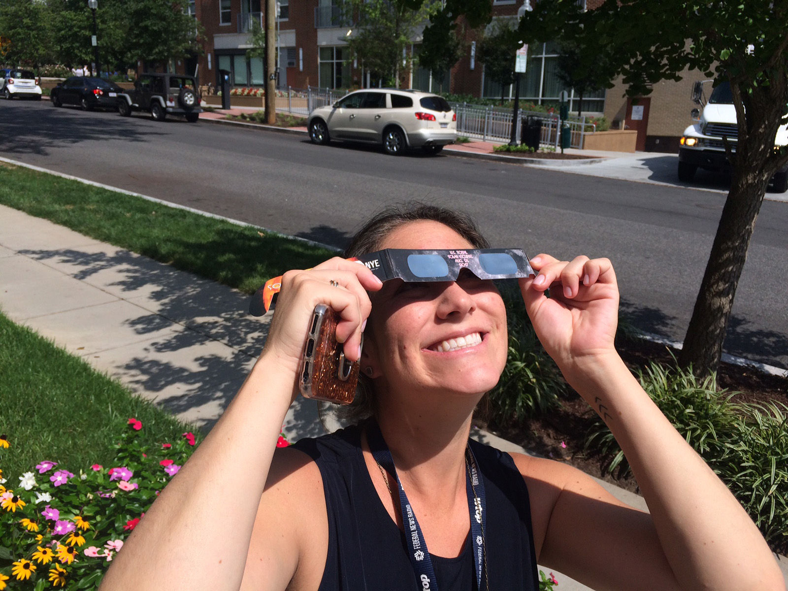 Rachel Nania, Living Editor at WTOP, takes a quick break from work to look up at the eclipse. (WTOP/Sarah Beth Hensley)
