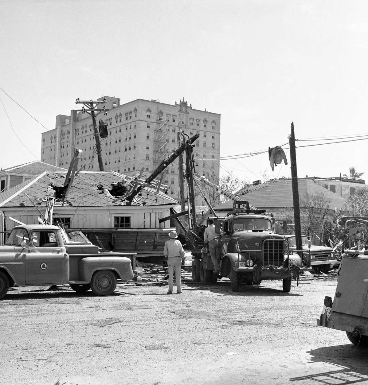 A telephone company truck lifts a snapped-off section of a pole from a hole in garage roof in Galveston, Texas on, Sept. 14, 1961. Bright sunshine and heavy equipment started to erase some of the scars of hurricane Carla on this island city. (AP Photo/Ed Kolenovsky)