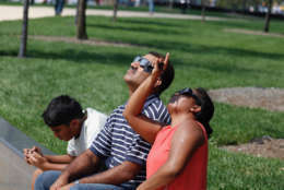 Shiva and Subash John take another look at the the solar eclipse, while their son Joshua looks at what is going on on social media. (WTOP/Kate Ryan)
