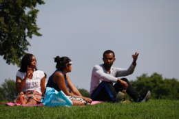 Joya Smith, Roshni Nedgungadi and Terrance Woodbury shared a spot on a grassy hill alongside the National Mall to watch the solar eclipse. (WTOP/Kate Ryan)