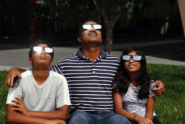 Joshua, Subash and Emily John of McLean, Virginia, take in the solar eclipse. (WTOP/Kate Ryan)