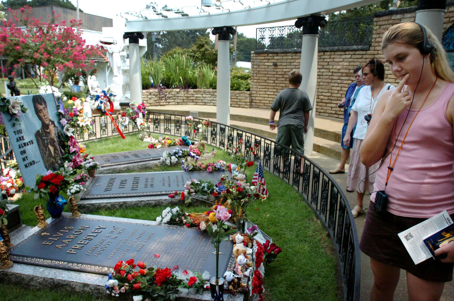 ** FILE ** In a file photo Chelsea Weir walks past the grave of Elvis Presley while taking a tour at Graceland in Memphis, Tenn., Wednesday, Aug. 3, 2005.    Elvis Presley Enterprises Inc. announced a new ad campaign on Monday, Akpril 16, 2007, as part of its effort to make the rock legend's former home Graceland a tourist destination on par with larger theme parks. (AP Photo/Mike Brown)