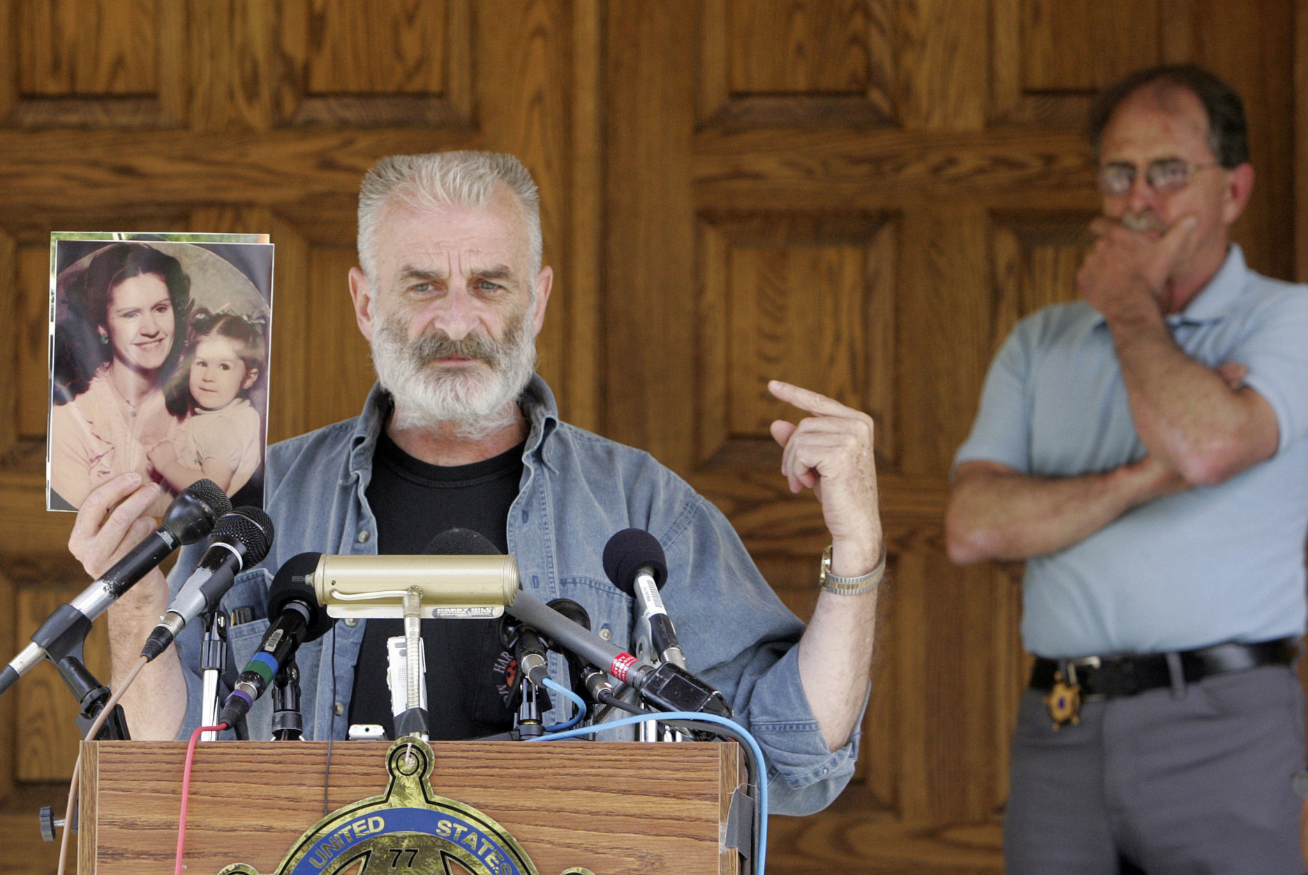 Ruby Ridge survivor Randy Weaver holds a photo of his wife Vicki, and 10-month-old daughter Elishiba as Ed Brown, back right, listens in Plainfield, N.H., Monday, June 18, 2007. Weaver's wife and child were killed in 1992 during a raid by federal agents. Ed and Elaine Brown have been convicted of tax evasion and have been holed up in their home refusing to pay back taxes. (AP Photo/Jim Cole)