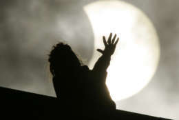 A woman looks at the moon partly covering the sun, during a partial solar eclipse, in St.Petersburg, Russia, Friday, Aug. 1, 2008. (AP Photo/Dmitry Lovetsky)