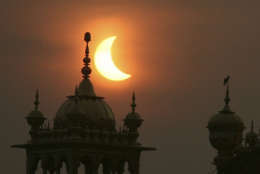 A partial solar eclipse is seen behind the Golden Temple, a Sikhs holiest shrine, in Amritsar, India, Wednesday, July 22, 2009. Millions of Asians turned their eyes skyward Wednesday as dawn suddenly turned to darkness across the continent in the longest total solar eclipse this century will see. Millions of others, seeing the rare event as a bad omen, shuttered themselves indoors. (AP Photo/Altaf Qadri)