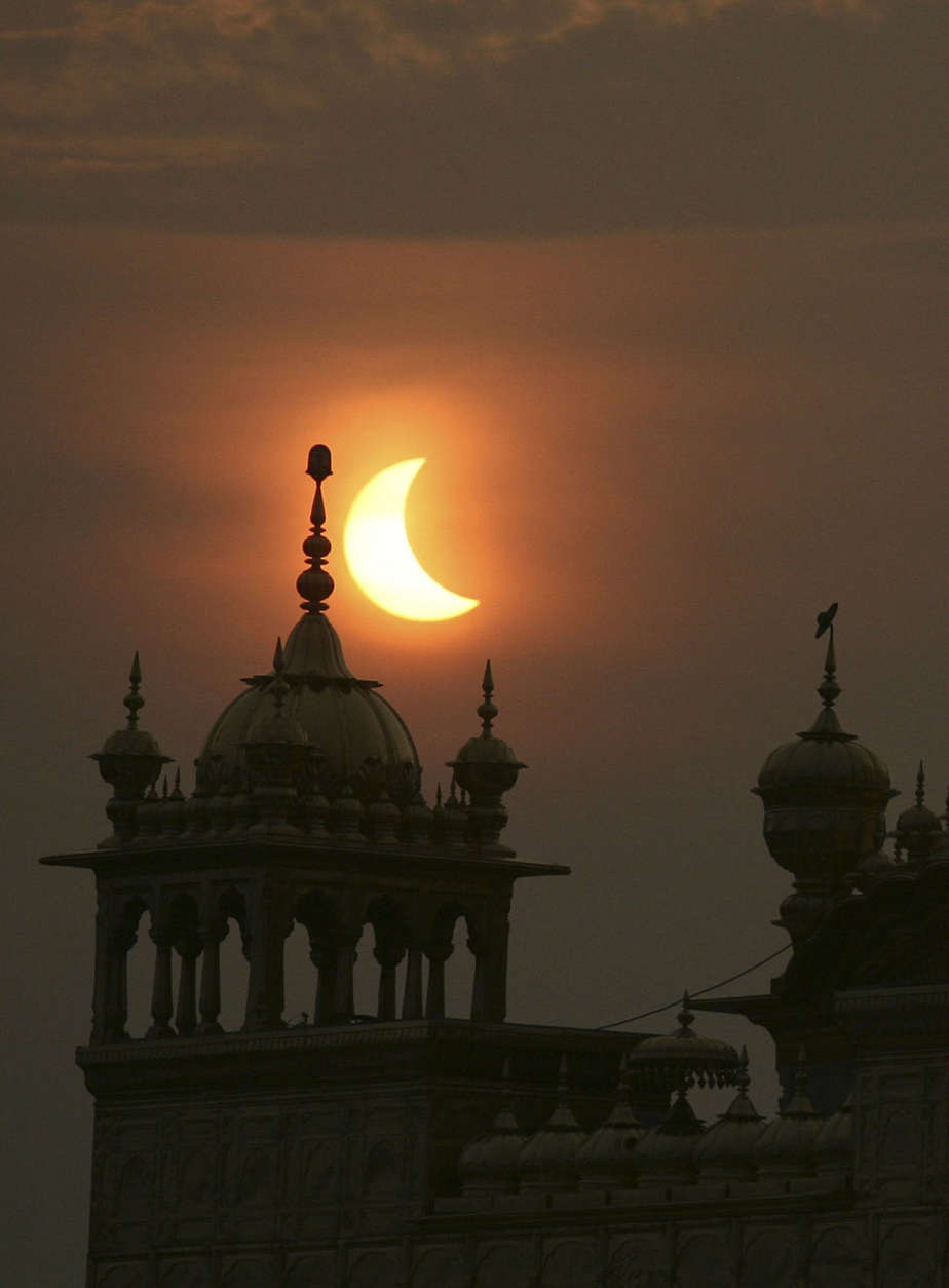 A partial solar eclipse is seen behind the Golden Temple, a Sikhs holiest shrine, in Amritsar, India, Wednesday, July 22, 2009. Millions of Asians turned their eyes skyward Wednesday as dawn suddenly turned to darkness across the continent in the longest total solar eclipse this century will see. Millions of others, seeing the rare event as a bad omen, shuttered themselves indoors. (AP Photo/Altaf Qadri)