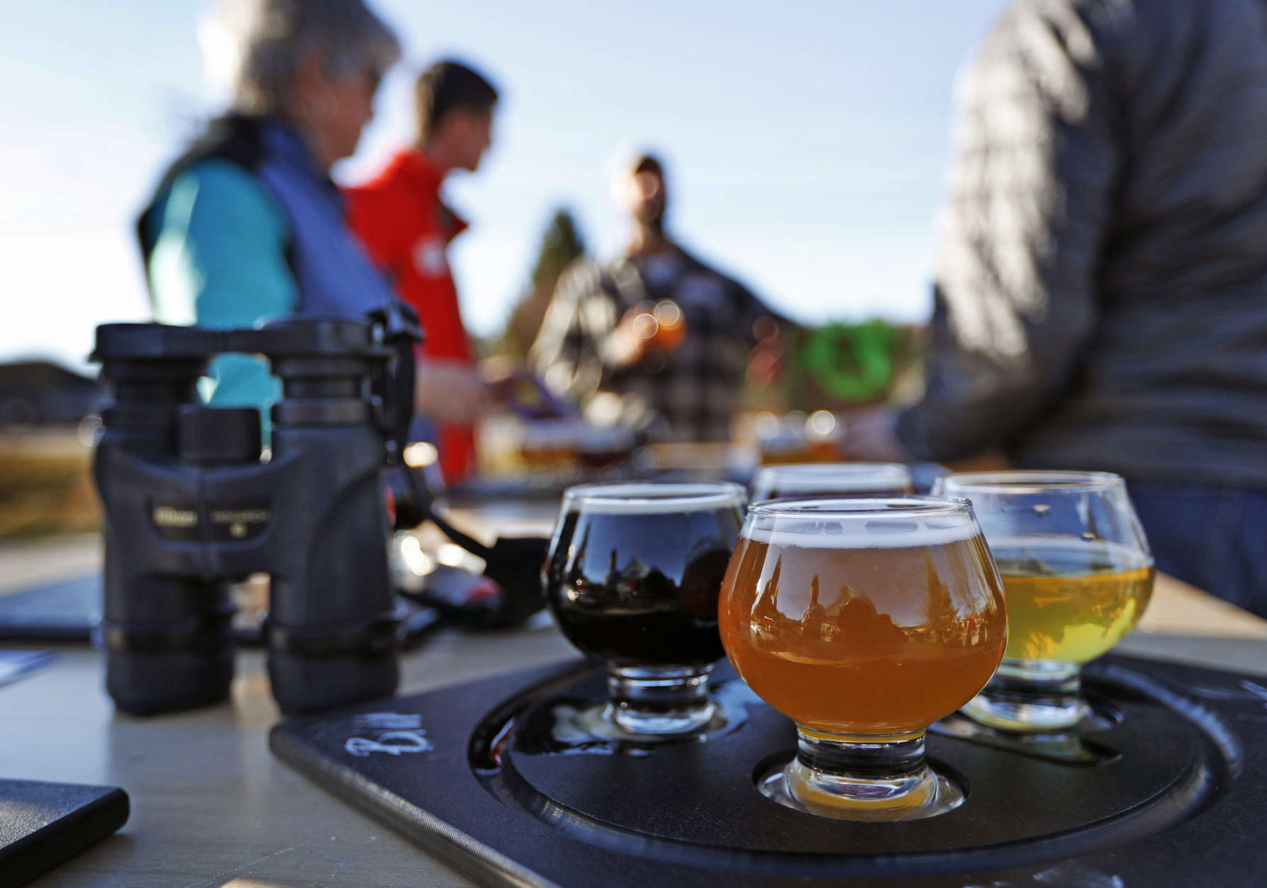In this Sunday, Nov. 13, 2016 photo a group of birding enthusiasts finish discuss their day while sampling a flight of beers at the Maine Brewing Company in Freeport, Maine. The Maine Brew Bus tour group combines bird watching and craft beers into popular trips throughout southern Maine. (AP Photo/Robert F. Bukaty)
