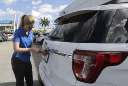 In this Tuesday, Jan. 17, 2017, photo, Ford sales consultant Yanaisis Milian removes the dealer tag on a sold 2017 Ford Explorer at an auto dealership in Hialeah, Fla. Automakers are reporting financial results Monday, April 3, 2017. (AP Photo/Alan Diaz)