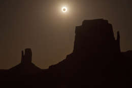 FILE - In this May 20, 2012, file photo, the new moon crosses in front of the sun creating an annular eclipse over West Mitten, left, and East Mitten buttes in Monument Valley, Ariz. Destinations are hosting festivals, hotels are selling out and travelers are planning trips for the total solar eclipse that will be visible coast to coast on Aug. 21, 2017. A narrow path of the United States 60 to 70 miles wide from Oregon to South Carolina will experience total darkness, also known as totality. (AP Photo/Julie Jacobson, File)