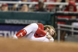 Washington Nationals' Bryce Harper grabs his knee after he was injured running to first during the first inning of the team's baseball game against the San Francisco Giants, Saturday, Aug. 12, 2017, in Washington. (AP Photo/Nick Wass)