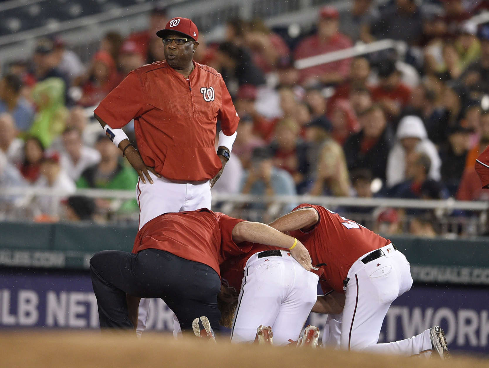 Washington Nationals manager Dusty Baker, top, stands on the field as Bryce Harper, bottom center, receives attention after he was injured during the first inning of a baseball game against the San Francisco Giants, Saturday, Aug. 12, 2017, in Washington. (AP Photo/Nick Wass)