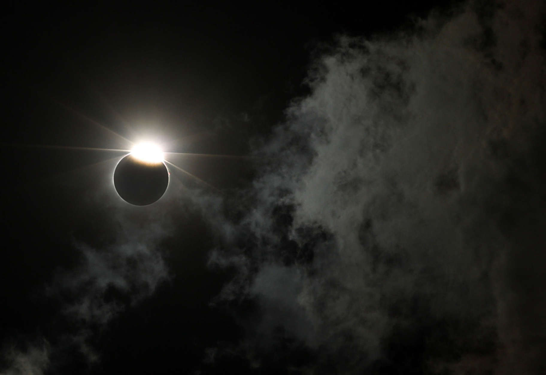 The moon partially blocks out the sun as a solar eclipse is seen through the clouds over the Gateway Arch Monday, Aug. 21, 2017, in St. Louis. The Gateway Arch was just a few miles outside of the path of totality. (AP Photo/Jeff Roberson)