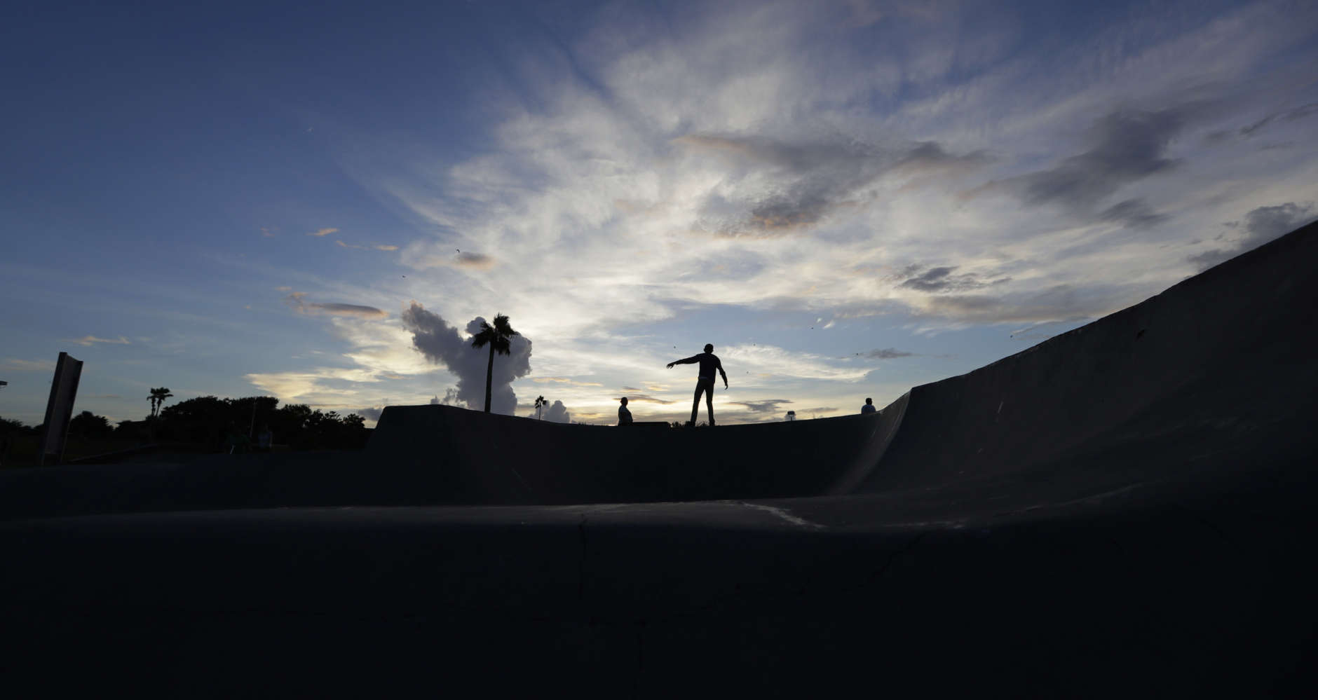 Jake High rides his skateboard at sunset, Thursday, Aug. 24, 2017, in Corpus Christi, Texas. Harvey intensified into a hurricane Thursday and steered for the Texas coast with the potential for up to 3 feet of rain, 125 mph winds and 12-foot storm surges in what could be the fiercest hurricane to hit the United States in almost a dozen years. (AP Photo/Eric Gay)