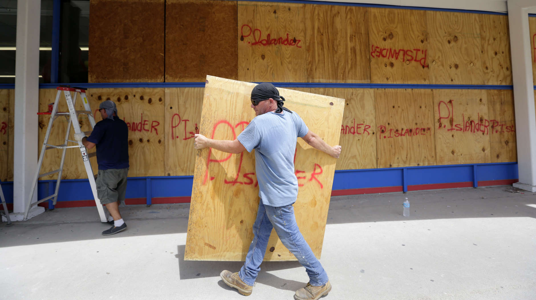 James Redford carries a sheet of plywood as he helps board up windows in preparation for Hurricane Harvey, Thursday, Aug. 24, 2017, in Corpus Christi, Texas. (AP Photo/Eric Gay)