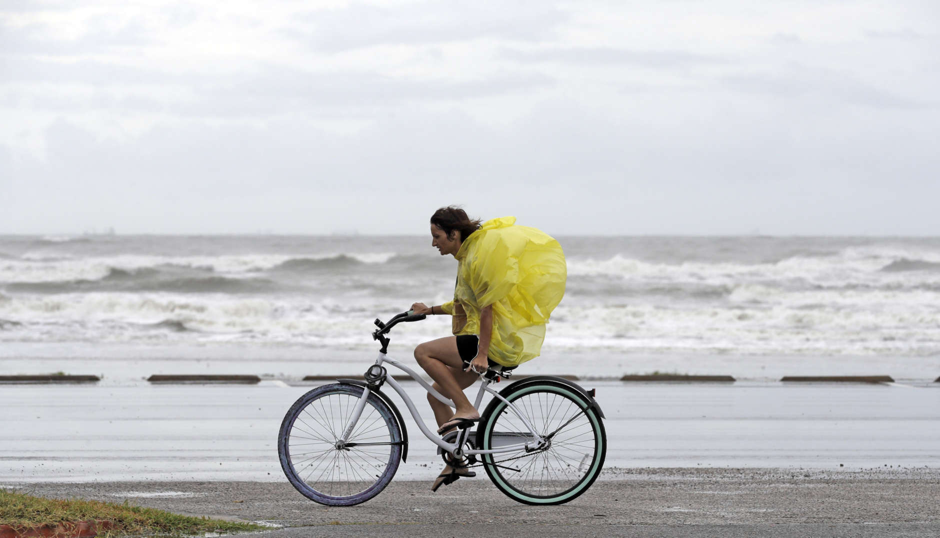 Emma Jewell rides her bicycle along Seawall Blvd. in Galveston, Texas as Hurricane Harvey intensifies in the Gulf of Mexico Friday, Aug. 25, 2017. Harvey is forecast to be a major hurricane when it makes landfall along the middle Texas coastline. (AP Photo/David J. Phillip)