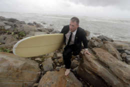 Mark Metzger wears a suit as he climbs over rocks as he carries his surfboard in Galveston, Texas as Hurricane Harvey intensifies in the Gulf of Mexico Friday, Aug. 25, 2017. Harvey is forecast to be a major hurricane when it makes landfall along the middle Texas coastline. (AP Photo/David J. Phillip)