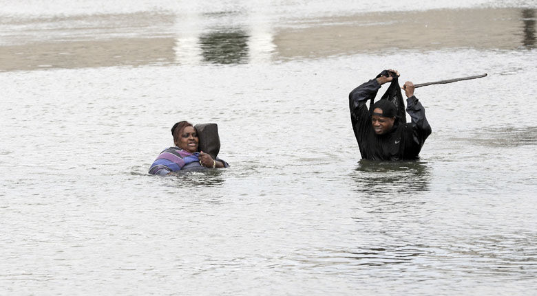 A man and woman try to navigate through floodwaters from Tropical Storm Harvey Sunday, Aug. 27, 2017, in Houston, Texas. (AP Photo/David J. Phillip)