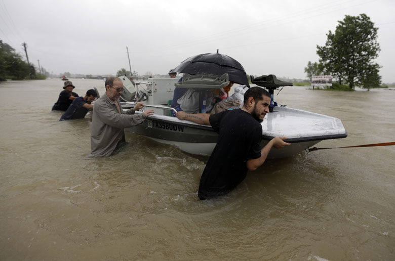 Evacuees are helped down Tidwell Road as floodwaters from Tropical Storm Harvey rise Monday, Aug. 28, 2017, in Houston. (AP Photo/David J. Phillip)
