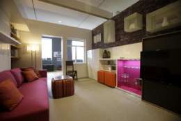 A stemware cabinet behind the TV, stacking tables hidden in an ottoman and a Murphy bed all help to make a 325 square foot model apartment seem roomy at an exhibit called "Making Room: Models for Housing New Yorkers" at the Museum of the City of New York in New York, Tuesday, Jan. 15, 2013. The exhibit grew out of the city's PlaNYC, which projected the city's population  will grow by about  600,000 people by 2030. (AP Photo/Seth Wenig)