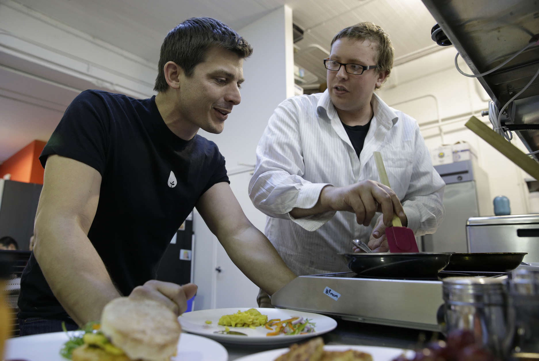 In this photo taken Tuesday, Dec. 3, 2013, CEO Josh Tetrick, left, watches as research and development chef Trevor Niekowal, right, makes a plant-based scrambled egg at Hampton Creek Foods in San Francisco.  Can plants replace eggs? A San Francisco startup backed by Bill Gates believes they can. Hampton Creek Foods is scouring the planet for plants that can replace chicken eggs in everything from cookies to omelets to French toast. Funded by prominent Silicon Valley investors, the upstart seeks to disrupt a global egg industry that backers say wastes energy, pollutes the environment, causes disease outbreaks and confines chickens to tiny spaces. (AP Photo/Eric Risberg)