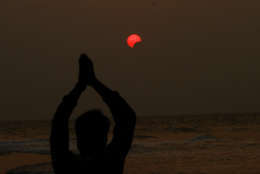 A fisherman prays during a partial solar eclipse in the sky over Bay of Bengal in Konark, 60 kilometers (37 miles) from the eastern Indian city Bhubaneswar, on Wednesday, March 9, 2016. (AP Photo/Biswaranjan Rout)