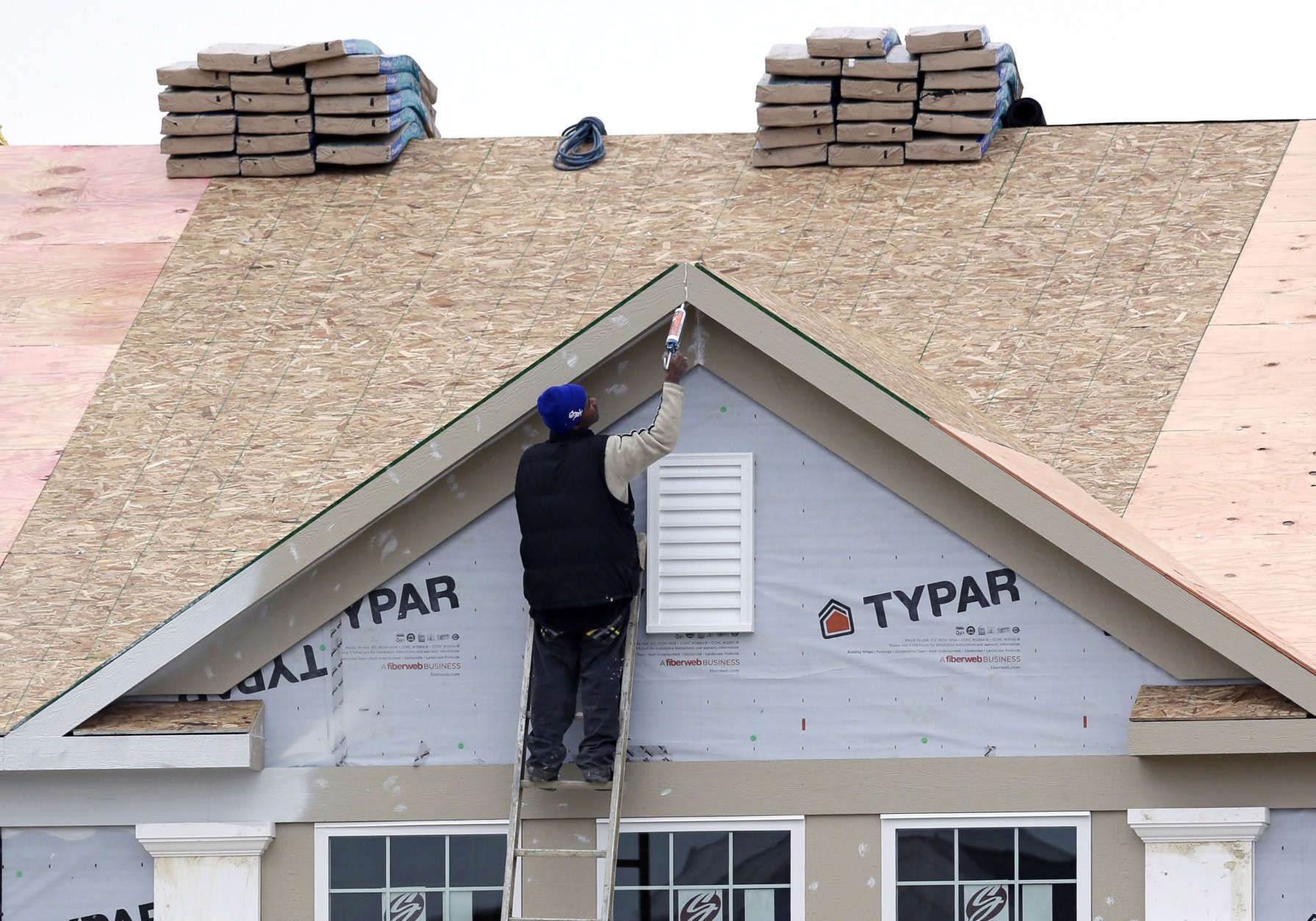 In this Monday, Nov. 11, 2013 photo, a worker caulks the peak of a new condominium complex under construction in Pepper Pike, Ohio. The Commerce Department releases new home sales for November on Tuesday, Dec. 24, 2013. (AP Photo/Tony Dejak)