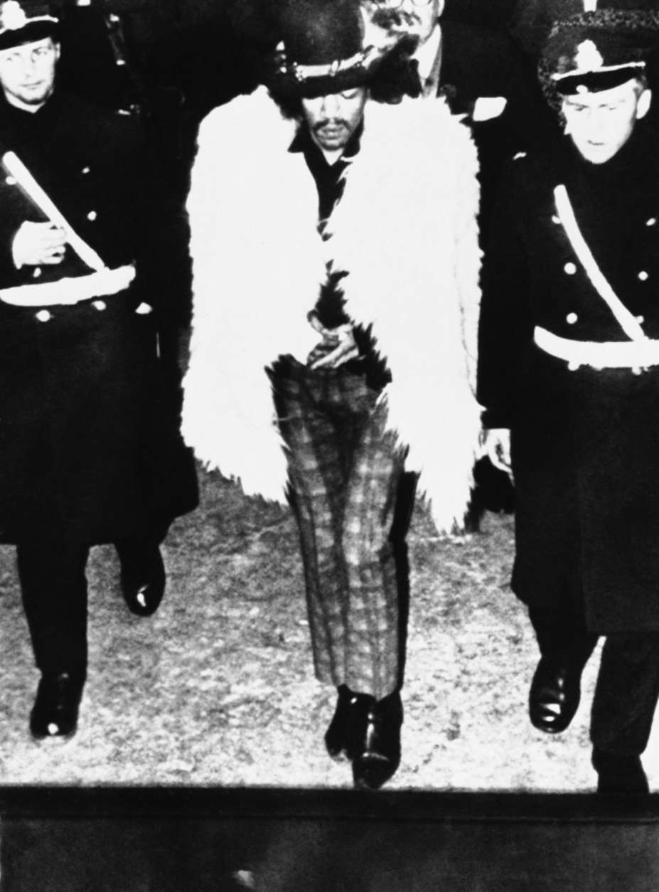 Shown in photo is 25-year old Pop singer Jimi Hendrix was jailed for drunkenness in Stockholm, Sweden in morning on Thursday, Jan. 5, 1968 after having gone berserk and destroyed everything in his room at Goteborg hotel Opa Len. Jimi Hendrix is escorted by two police. (AP Photo)