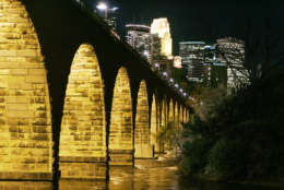FILE - In this Oct. 17, 2005 file photo, the Minneapolis skyline is illuminated in the background from the historic Stone Arch Bridge over the Mississippi River.  (AP Photo/Jim Mone,File)