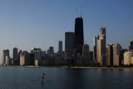 A paddle boarder coasts along the smooth surface of Lake Michigan with the downtown skyline in the background Wednesday morning, Aug. 20, 2014, in Chicago. (AP Photo/Kiichiro Sato)