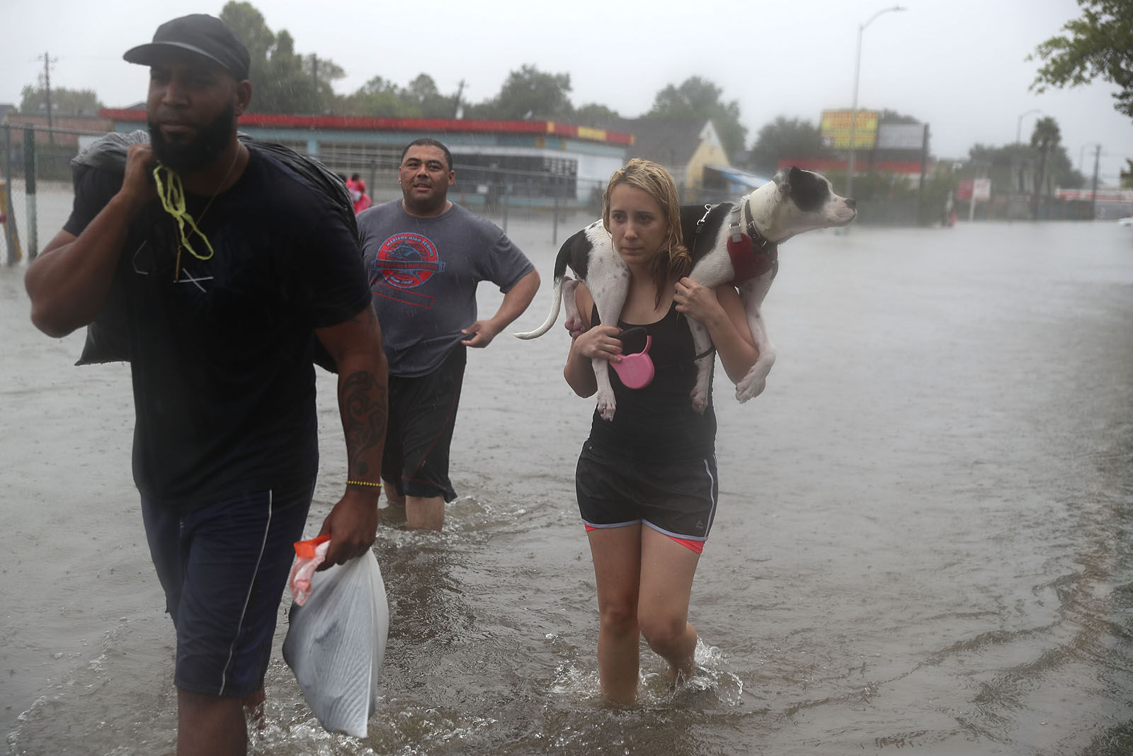Naomi Coto carries Simba on her shoulders as they evacuate their home after the area was inundated with flooding from Hurricane Harvey on August 27, 2017 in Houston, Texas. Harvey, which made landfall north of Corpus Christi late Friday evening, is expected to dump upwards to 40 inches of rain in Texas over the next couple of days.  (Photo by Joe Raedle/Getty Images)