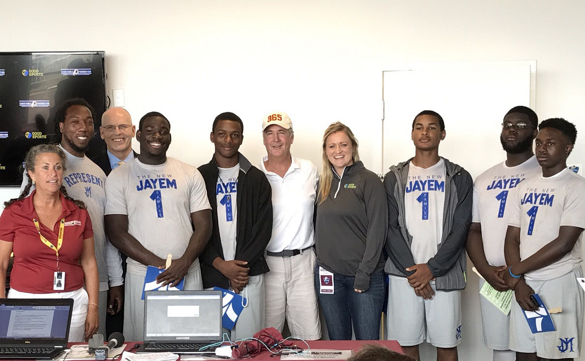Jane Rogers (left) and Redskins GM Bruce Allen (center) stand with Richmond Public Schools interim Superintendent Thomas Krantz and members of the John Marshall football team. (WTOP/George Wallace)