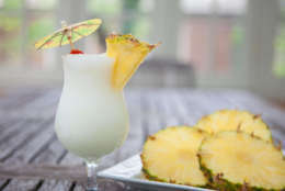 Pina Colada and Pineapple on a plate on a wooden table.