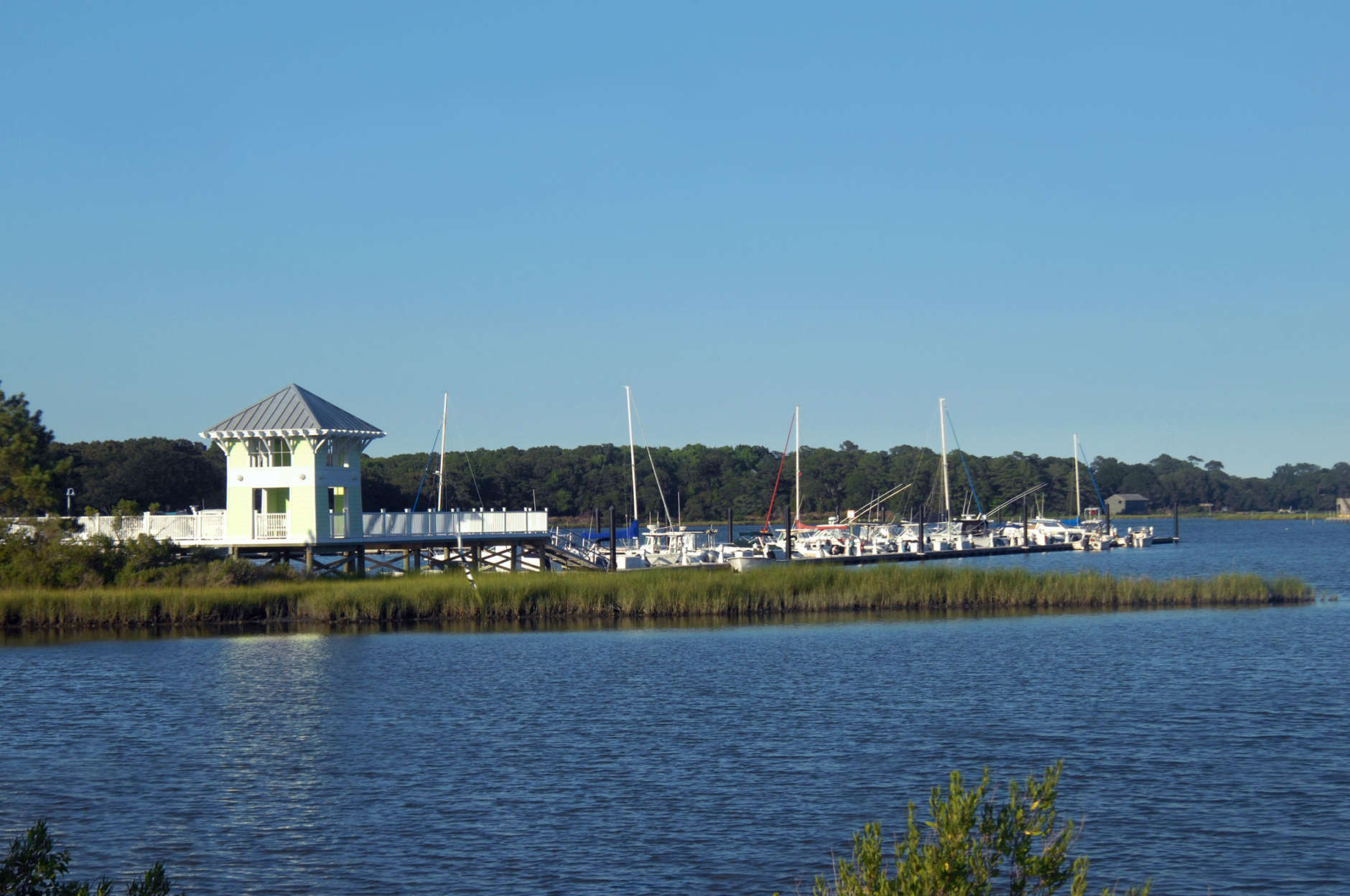 Cape Charles Marina has boats and yachts docked at pier.  Evening light darkens water and landscape on Assateague Island, Virginia.