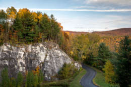 Road through thick fall foliage and marble rock formation