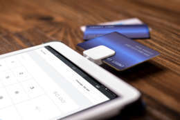 Credit card payment on a swipe or chip reader app on a tablet used by small or online businesses.  The electronic device is used as a modern cash register or for banking.  The image depics modern method of currency transactions for business.