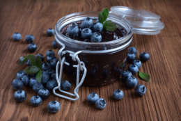 Homemade blueberry jam in a glass jar on a wooden table
