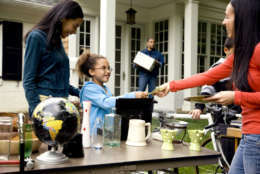 Young girl handles the cash register at suburban yard sale
