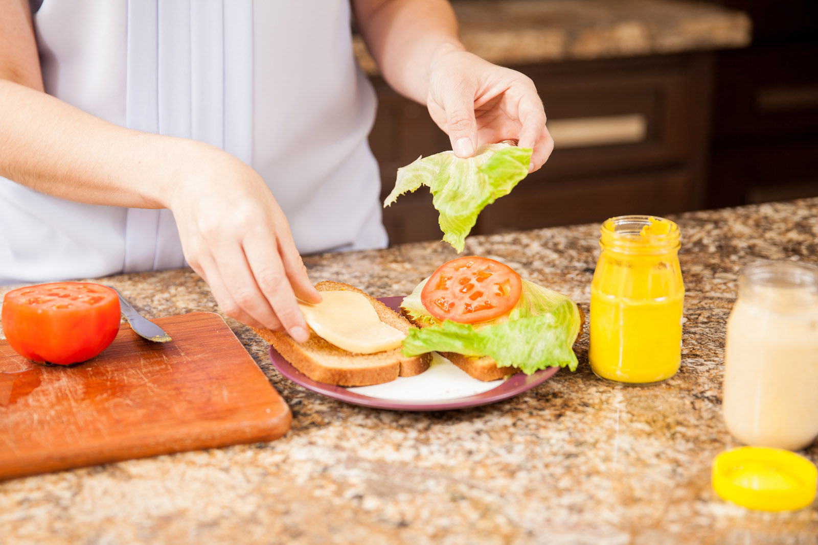 Closeup of the hands of young woman preparing a sandwich at home (Thinkstock)