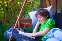 Happy school boy reading a book in the backyard. Child relaxing in a garden swing with books. Kids read during summer vacation. Children studying. Teenager kid doing homework outdoors. (Thinkstock)