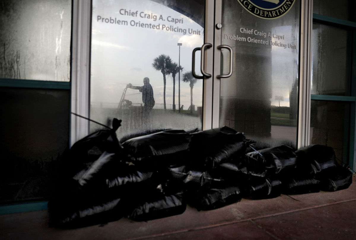 Sandbags sit outside a police station office as a worker secures the grounds of a hotel along the beach ahead of Hurricane Irma in Daytona Beach, Fla., Friday, Sept. 8, 2017. Coastal residents around South Florida have been ordered to evacuate as the killer storm closes in on the peninsula for what could be a catastrophic blow this weekend. (AP Photo/David Goldman)
