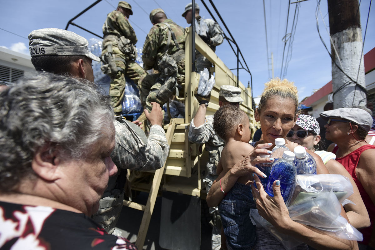 In this Sept. 24, 2017, photo, National Guard Soldiers arrive at Barrio Obrero in Santurce to distribute water and food among those affected by the passage of Hurricane Maria, in San Juan, Puerto Rico.  Federal aid is racing to stem a growing humanitarian crisis in towns left without fresh water, fuel, electricity or phone service by the hurricane. (AP Photo/Carlos Giusti)