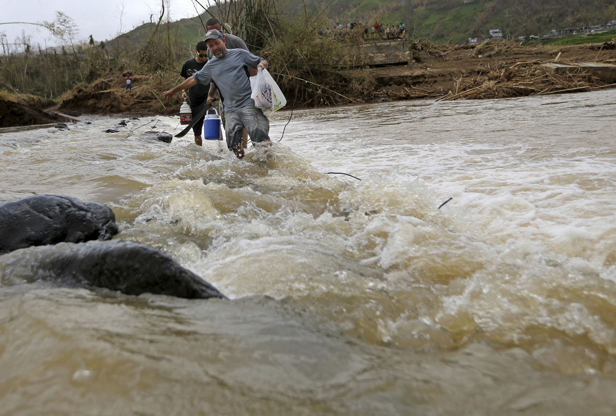 Men cross the Rio San Lorenzo de Morovis, since the bridge was swept away by Hurricane Maria, in Morovis, Puerto Rico, Wednesday, Sept. 27, 2017. A week since the passing of Maria many are still waiting for help from anyone from the federal or Puerto Rican government. But the scope of the devastation is so broad, and the relief effort so concentrated in San Juan, that many people from outside the capital say they have received little to no help. (AP Photo/Gerald Herbert)