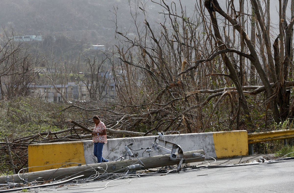 A woman walks past damaged trees and downed power lines, in the aftermath of Hurricane Maria, in Yabucoa, Puerto Rico, Tuesday, Sept. 26, 2017. Governor Ricardo Rossello and Resident Commissioner Jennifer Gonzalez, the islandâ€™s representative in Congress, have said they intend to seek more than a billion in federal assistance and they have praised the response to the disaster by President Donald Trump, who plans to visit Puerto Rico next week, as well as FEMA Administrator Brock Long.  (AP Photo/Gerald Herbert)