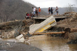 People sit on both sides of a destroyed bridge that crossed over the San Lorenzo de Morovis river, in the aftermath of Hurricane Maria, in Morovis, Puerto Rico, Wednesday, Sept. 27, 2017. A week since the passing of Maria many are still waiting for help from anyone from the federal or Puerto Rican government. But the scope of the devastation is so broad, and the relief effort so concentrated in San Juan, that many people from outside the capital say they have received little to no help. (AP Photo/Gerald Herbert)