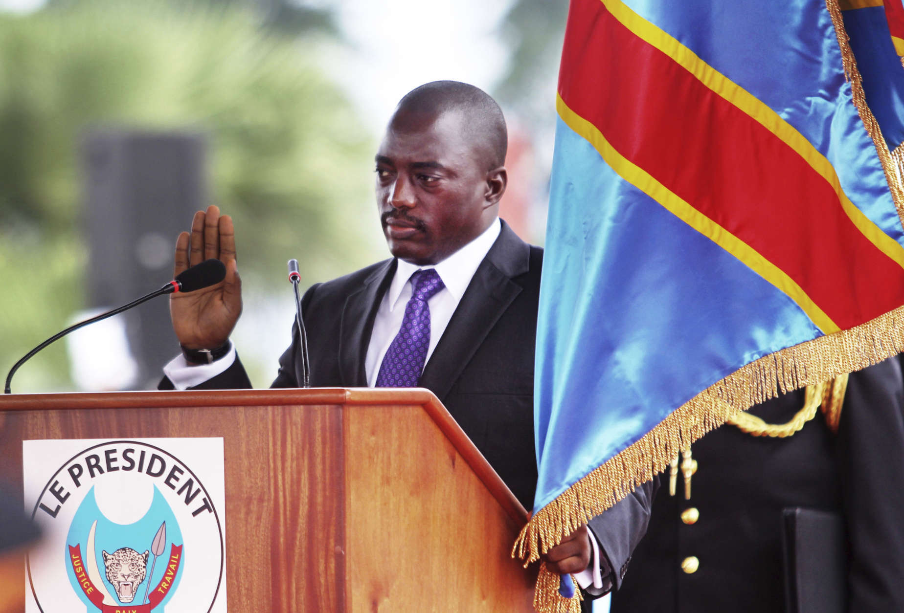 Incumbent Congo President Joseph Kabila holds the Congolese flag as he takes the oath of office as he is sworn in for another term, in Kinshasa, Congo Tuesday, Dec. 20, 2011. The president of sub-Saharan Africa's largest nation pledged to unify the country after an election that was criticized by international observers. The country's top opposition candidate, meanwhile, planned his own inauguration in a move that could spark political chaos. (AP Photo/John Bompengo)