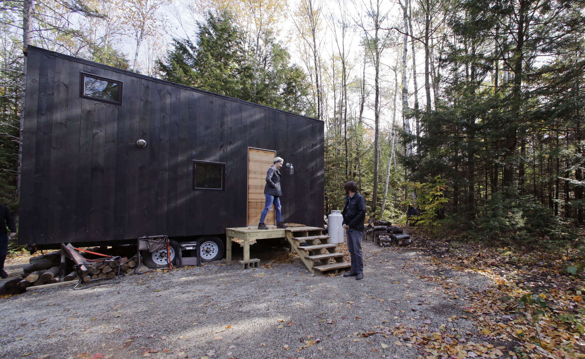In this Tuesday, Oct. 20, 2015 photo, Hilary Lentz, of Pittsburgh, Pa., and her husband Shane leave the tiny house which they rented for a weekend in Croydon, N.H. As the tiny house phenomenon sweeps the nation, Harvard's Millennial Housing Lab thinks a tryout is in order for people toying with radically downsizing their lives. Its new "Getaway" project gives the curious an opportunity to spend a night or two in one of three tiny houses and get a real feel for the lifestyle before taking the plunge. (AP Photo/Charles Krupa)