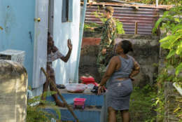 Two local women chat as a Dutch Marine helps out in preparation for the arrival Hurricane Maria, in Oranjestad, Statia, on the Leeward Islands, Monday, Sept. 18 2017. Maria has intensified into a Category 5 hurricane as its eye is approaching Dominica in the eastern Caribbean, the U.S. Hurricane Center said in a statement on Monday evening. (AP Photo/Stephan Kogelman)