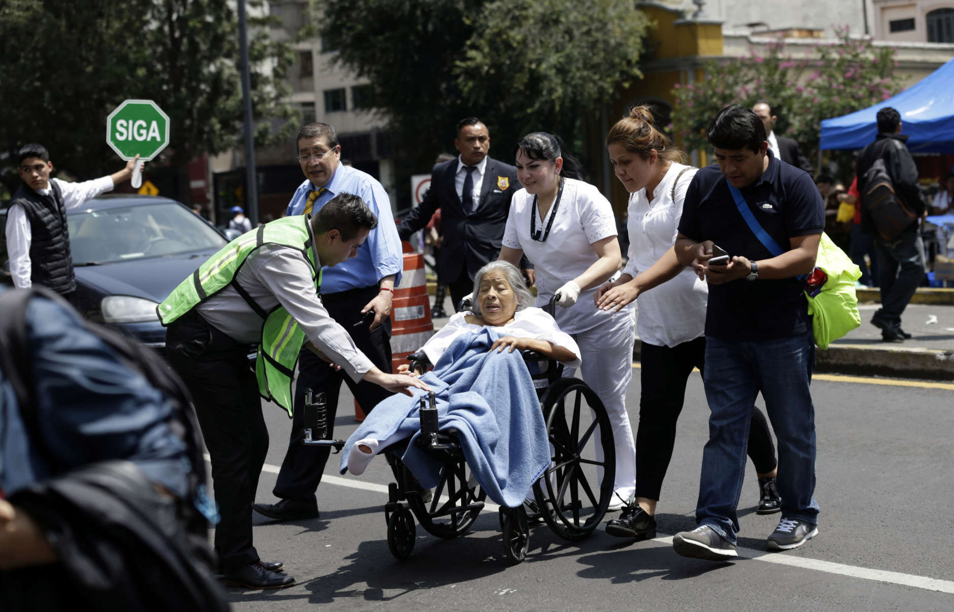 A woman in a wheelchair is evacuated from a clinic as people gather along Paseo de la Reforma Avenue after an earthquake in Mexico City, Tuesday Sept. 19, 2017. A powerful earthquake jolted central Mexico on Tuesday, causing buildings to sway sickeningly in the capital on the anniversary of a 1985 quake that did major damage. (AP Photo/Marco Ugarte)