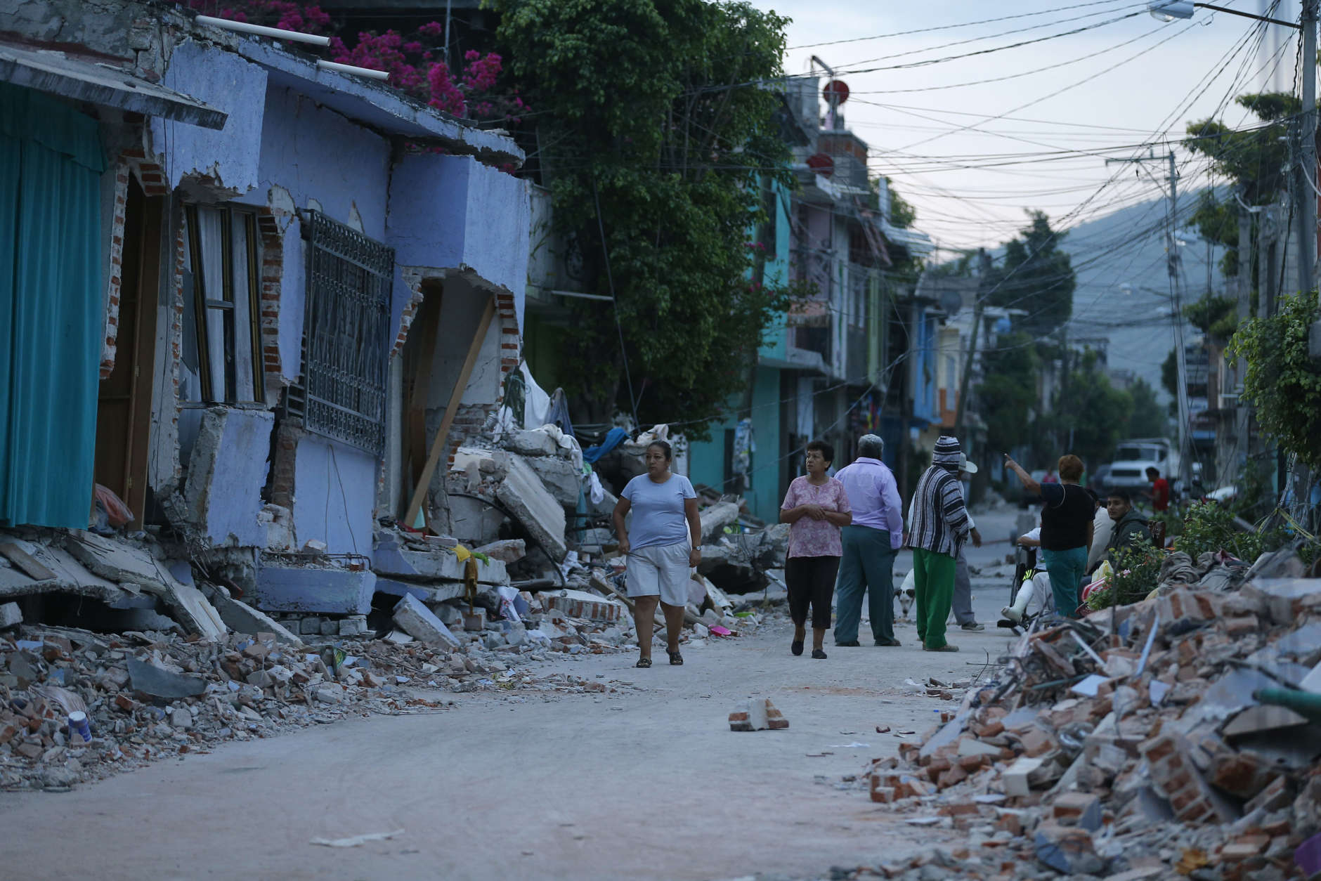 Residents stand next to buildings damaged by a 7.1 earthquake, in Jojutla, Morelos state, Mexico, Wednesday, Sept. 20, 2017. Police, firefighters and ordinary Mexicans are digging frantically through the rubble of collapsed schools, homes and apartment buildings, looking for survivors of Mexico's deadliest earthquake in decades as the number of confirmed fatalities climbed to 248. (AP Photo/Eduardo Verdugo)